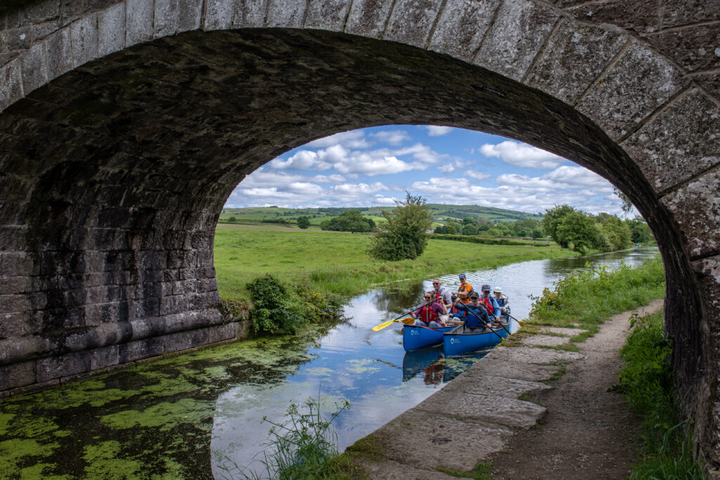 Group canoeing under canal bridge