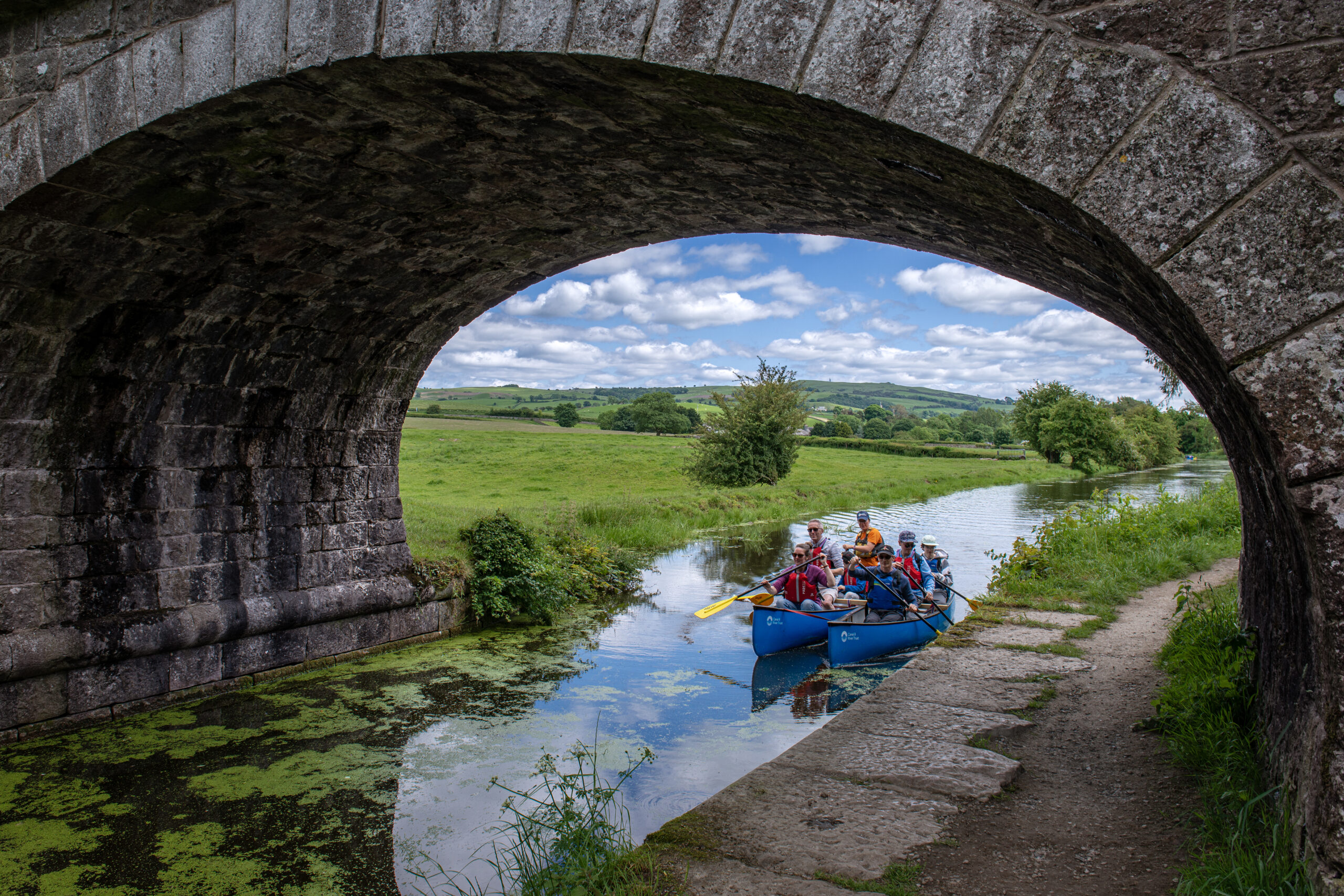 Group canoeing under canal bridge